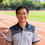 深圳市第三中学体育教研组长李建明老师的正面半身照片，他穿着运动polo衫，面带微笑站在学校操场上